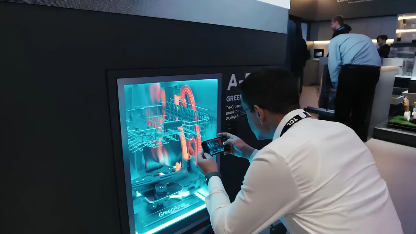 Демонстраційна посудомийка Midea з підсвіченою системою Tri-GreenApex на стенді Midea, відвідувач знімає її на смартфон