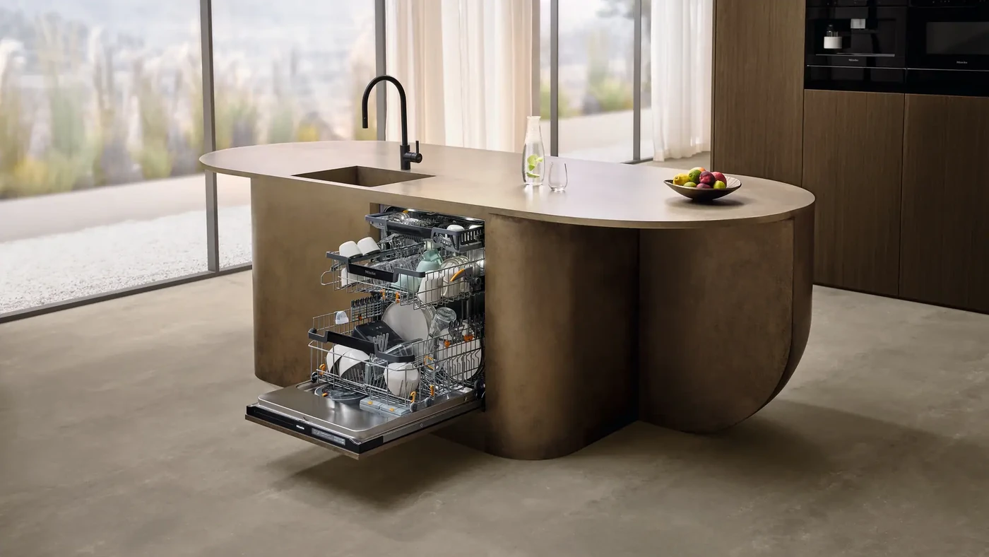 Відчинена посудомийка Miele G8 Diamond із посудом у висунутих кошиках, вбудована в кухонний острів
