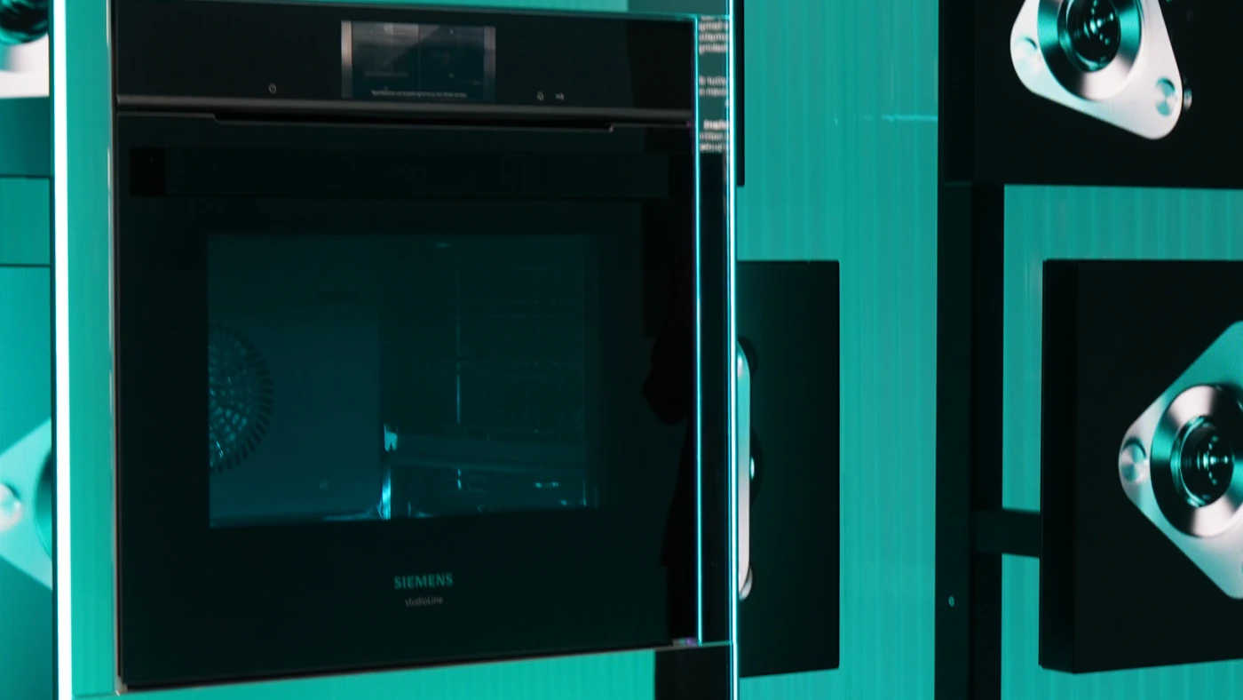 Вбудована духовка Siemens iQ700 з дисплеєм над дверцятами в бірюзовому освітленні стенда